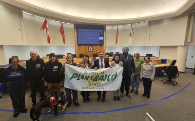 Grupo de ativistas do Tratado Plant Based com autoridades da cidade de Brampton, incluindo o prefeito Brown e os vereadores Brar e Tor, segurando uma faixa que diz "Apoie o Tratado Plant Based" durante uma reunião para apoiar oficialmente o tratado